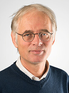 Dirk van der Marel mit Brille und grauem Haar vor weißem Hintergrund.